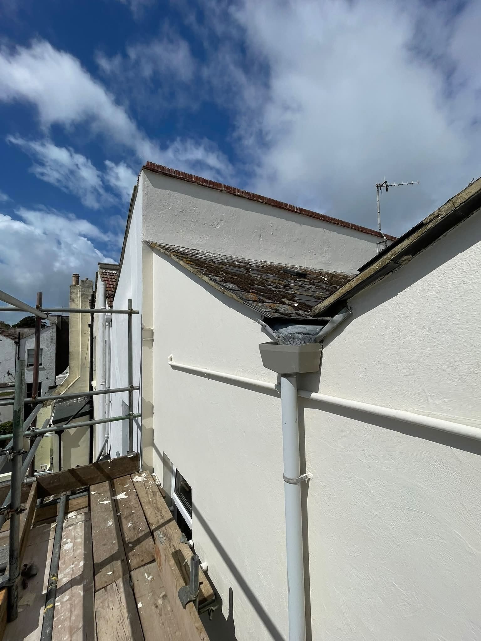 Freshly painted rendered wall with clean gutters and downpipe